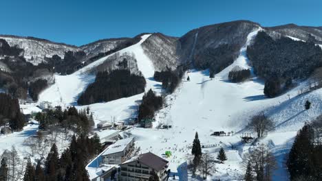 Static-shot-of-bottom-of-ski-run,-skiers-arriving-at-base-of-mountain-lining-up-for-the-chairlifts