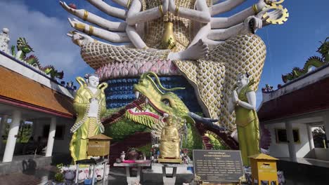 Bright-sunny-day-at-Koh-Samui-temple-with-large-Buddha-statue-and-dragon-sculptures,-blue-sky
