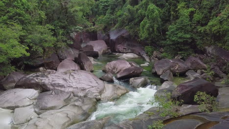 From-a-relaxed-aerial-viewpoint,-we-observe-the-Babinda-Boulders-in-Cairns,-Australia,-highlighting-the-swift-currents-flowing-amidst-its-granite-structures,-embraced-by-verdant-foliage