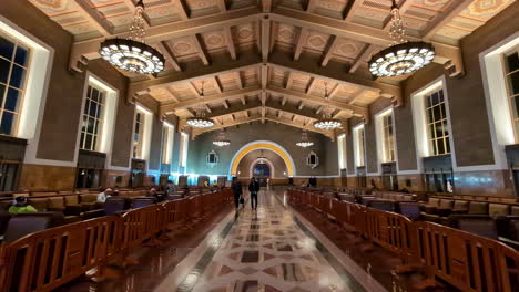 People-walk-inside-hall-at-Union-Station-Los-Angeles-transportation-hub-walk-and-sit-slow-motion-revealing-shot