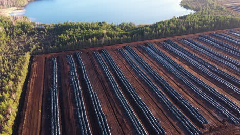 Peat-extraction-field-near-lake-in-aerial-panorama-view