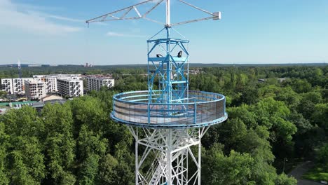 Vista-Aérea-De-La-Torre-De-Paracaídas-Con-Vista-De-Construcción-De-Fincas-En-La-Distancia