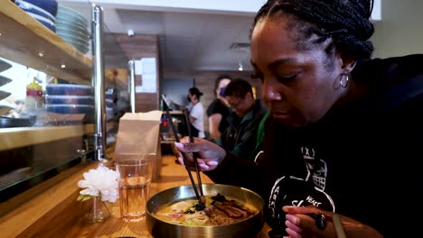 black-woman-enjoying-a-savory-bowl-of-ramen-at-a-cozy-noodle-bar