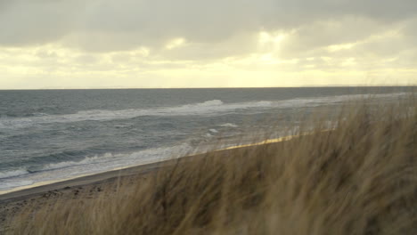 Ruhiger-Blick-Von-Einer-Mit-Seegras-Bedeckten-Düne-Auf-Die-Wellen,-Die-An-Den-Strand-Rollen