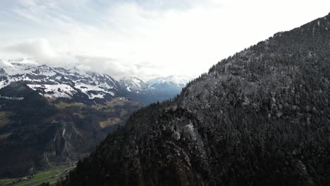 A-captivating-panoramic-view-unveils-snow-dusted-forests-crowning-the-rolling-hills-near-Glarus-amidst-the-Swiss-Alps,-where-the-rugged-beauty-of-nature-meets-the-tranquility-of-alpine-landscapes