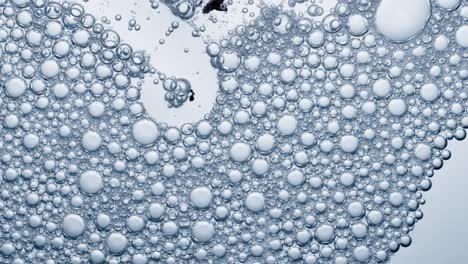 Multitude-of-air-bubbles-in-a-soap-solution,-bubbles-burst-on-contact-with-air