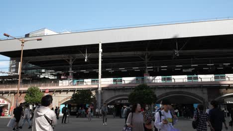 Passersby-stroll-near-Shimbashi-Station-in-Tokyo,-embodying-the-concept-of-urban-mobility-and-bustling-city-life