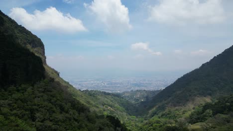 Dolly-Shot-of-Drone-Heading-Off-into-Mountains-with-View-of-San-Jose-Costa-Rica-Off-in-the-Distance