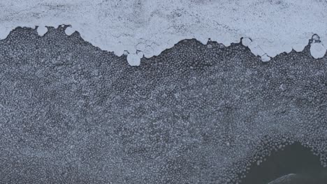 Ein-Zugefrorener-See-Mit-Komplizierten-Eismustern-Und-Schneeflecken,-Luftaufnahme