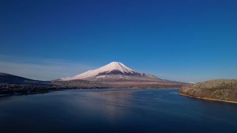 Snow-Capped-Mt-Fuji-With-Blue-Sky-and-Forest-With-Lake-In-Winter-Drone