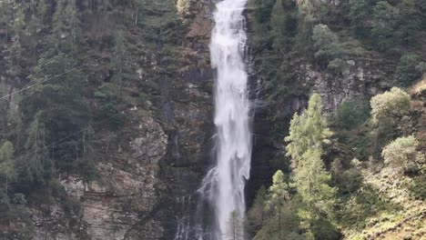 Pan-Down-of-Tall-Waterfall-Splashing-Water-on-Rocks-Below