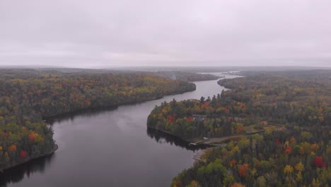 Drohnenaufnahme-Eines-Fluges-über-Einen-Wunderschönen-Fluss,-Umgeben-Von-Bäumen,-Die-Im-Herbst-Ihre-Farbe-ändern