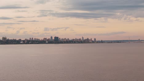 A-stunning-view-of-downtown-Posadas-from-the-river-during-sunset,-showcasing-the-city's-beauty-against-the-colorful-evening-sky