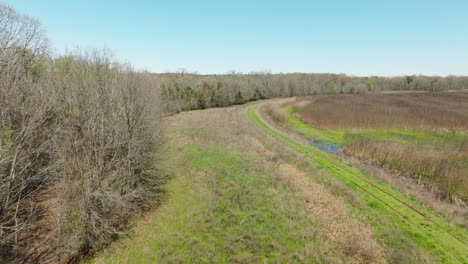 Bell-slough-wildlife-area-with-lush-green-trail-in-Arkansas,-sunny-day,-aerial-view