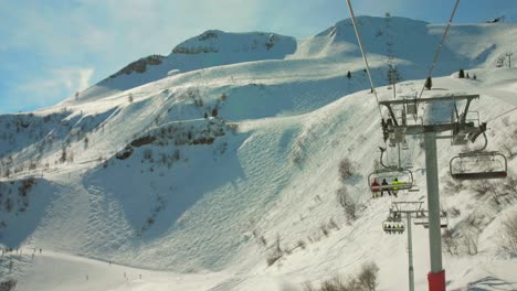 Tourists-Riding-Chairlift-Over-French-Alps-In-Ski-Resort-During-Sunny-Day-In-France