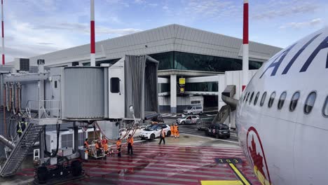 Operaciones-Terrestres-Para-Aviones-De-Air-Canada-En-La-Puerta-De-La-Terminal-Del-Aeropuerto-Y-Aerobridge-O-Pasarela-Separada-Con-Operadores-Trabajando-En-El-Asfalto