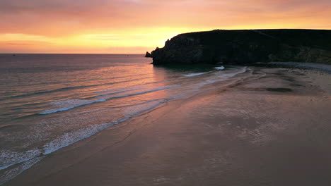 Upward-Establishing-Aerial-of-Sun-Setting-Over-Ocean,-Beach-and-Old-Ruins