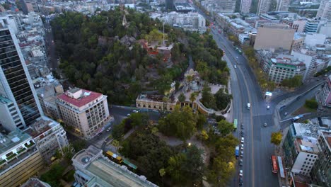 Aerial-panoramic-drone-of-Santiago-de-chile-street-traffic-Santa-Lucia-Hill-urban-green-area-around-city-neighborhood-buildings-and-Neptune-Fountain
