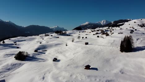 Wooden-farmhouses-in-Alpine-landscape-with-snow,-aerial