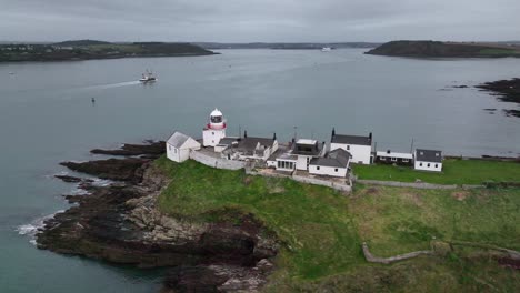 Drone-video-of-Roches-Point-Lighthouse-in-Roches-Point,-East-Cork,-Ireland,-showing-a-ship,-Crosshaven-and-Cobh-in-the-distance