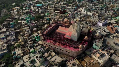 Cámara-De-Vista-Aérea-De-Drones-Que-Va-Hacia-Atrás,-Hay-Muchas-Personas-Jugando-Dhulet-Y-Muchas-Personas-Tienen-Darshan-En-El-Templo-Y-Están-Saliendo