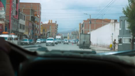 Driving-through-Uyuni-streets-with-visible-local-shops-and-bustling-traffic,-daytime,-urban-scene,-dashcam-view