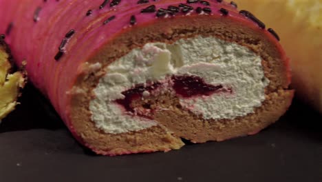 Close-up-detail-shot-slider-of-slider-shot-of-cake-rolls-brazo-gitano-swiss-roll-desserts-collection-chocolate-ferrero-cheese-butter-jelly-berries-cherry-with-black-background