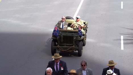 Senior-veteran-riding-on-the-military-jeep,-driving-down-the-street,-participating-the-annual-Anzac-Day-parade-tradition