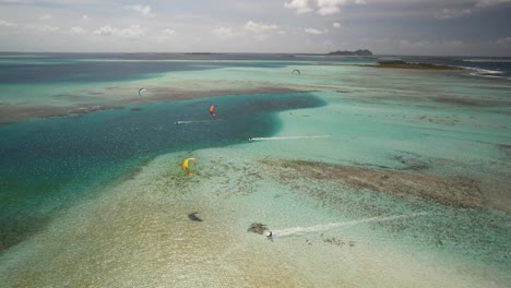 Kite-surfers-gliding-over-clear-turquoise-waters-at-cayo-de-agua,-los-roques,-aerial-view