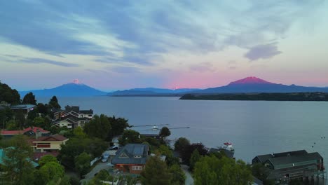 Panoramic-drone-video-at-dusk-of-Lake-Llanquihue-and-the-volcanoes,-Osorno-and-Calbuco-seen-from-Puerto-Varas,-Chile