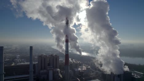 Aerial-dolly-shot-of-a-coal-fired-heating-power-plant-with-thick-white-smoke-coming-from-the-chimney,-environmental-pollution-concept