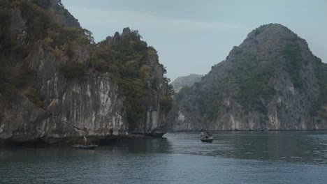 Sailing-Past-Local-Fisherman-Past-Impressive-Limestone-Karsts-In-Lan-Ha-Bay-Over-Calm-Sea-Waters,-Vietnam
