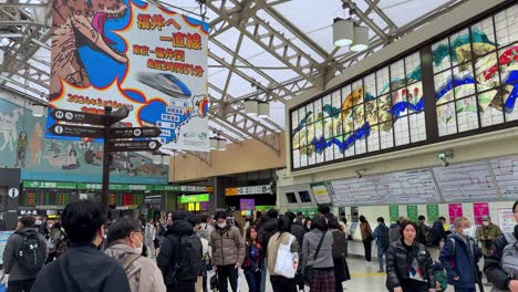 Concurrida-Estación-De-Tren-En-Japón-Con-Viajeros-Y-Anuncios-Coloridos,-Carteles-Elevados