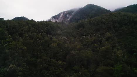 Fly-through-steam-rising-from-geothermal,-volcanic-forest-and-mountain-in-New-Zealand,-North-Island