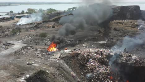 Establishing-Shots-In-the-drone-camera,-many-people-are-burning-plastic-waste-and-many-roads-are-visible-on-the-other-side