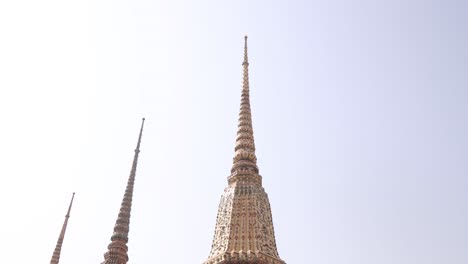 looking-up-at-towering-detailed-pagoda-spires-in-a-buddhist-temple-complex-in-the-Rattanakosin-old-town-of-Bangkok,-Thailand