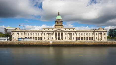 Lapso-De-Tiempo-Del-Edificio-Histórico-De-La-Casa-Personalizada-En-La-Ciudad-De-Dublín-Durante-El-Día-Con-Nubes-En-El-Cielo-Reflejándose-En-El-Río-Liffey-En-Irlanda