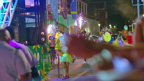 Enfoque-En-Rack-Entre-Turistas-Y-Artistas-Encendiendo-Fuegos-Artificiales-Durante-El-Desfile-De-Carnaval-Por-La-Noche.