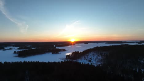 Drohnenvideo-über-Einem-Wald-Und-Einem-Zugefrorenen-See-Bei-Sonnenuntergang