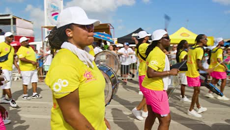 Pan-across-drummers-in-yellow-and-pink-strutting-down-Carnaval-parade