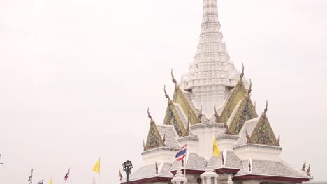 looking-up-at-towering-detailed-white-pagoda-spire-in-a-buddhist-temple-complex-in-the-Rattanakosin-old-town-of-Bangkok,-Thailand