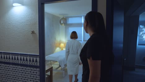 Slow-motion-shot-of-a-masseuse-showing-a-woman-to-the-bed-ready-for-the-treatment