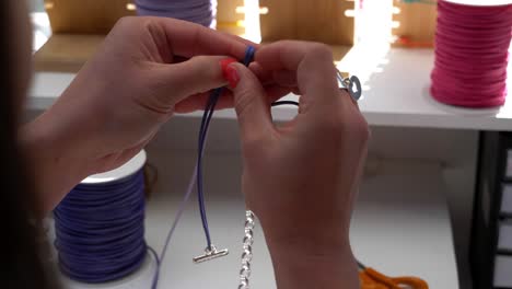 Close-up-shot-of-a-jeweler-tying-knots-making-a-finished-bracelet