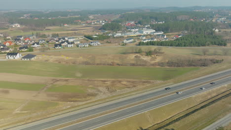 Elevated-highway-overpass-cutting-through-a-rural-landscape-with-sparse-traffic,-under-the-clear-sky