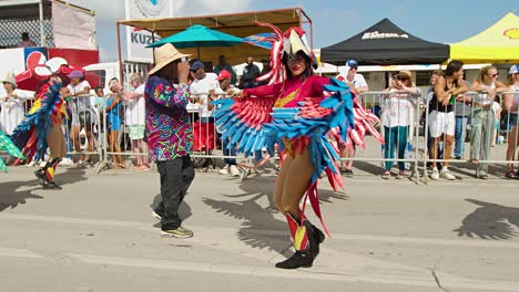 Alas-De-Disfraz-De-Loro-Rojo-Y-Azul-Con-Mujer-Bailando-Y-Girando-En-Las-Calles