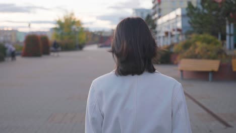 View-from-back-of-female-brunette-walk-on-Prague-city-urban-area-sidewalk