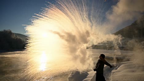 Heißes-Wasser-In-Die-Luft-Werfen,-Das-Sich-Vor-Einem-Wunderschönen-Wintersonnenuntergang-In-Schnee-Verwandelt