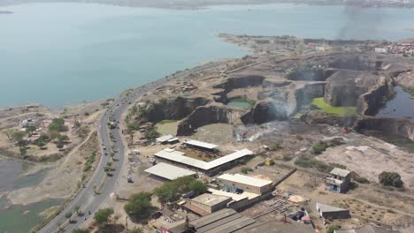 ESTABLISHING-SHOTS-Drone-Camera-is-moving-to-the-side-where-water-and-the-city-can-be-seen-around-where-plastic-waste-is-burning-in-a-large-dumping-yard