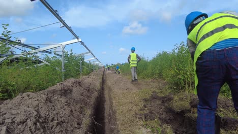 Afrikanischer-Arbeiter-Mit-Helm-Und-Handschuhen-Gräbt-Einen-Graben-Für-Den-Bau-Einer-Solaranlage-In-Jambur,-Gambia