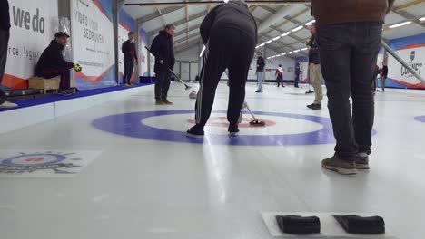 Player-brushing-curling-stone-with-broom-out-of-the-house-on-ice